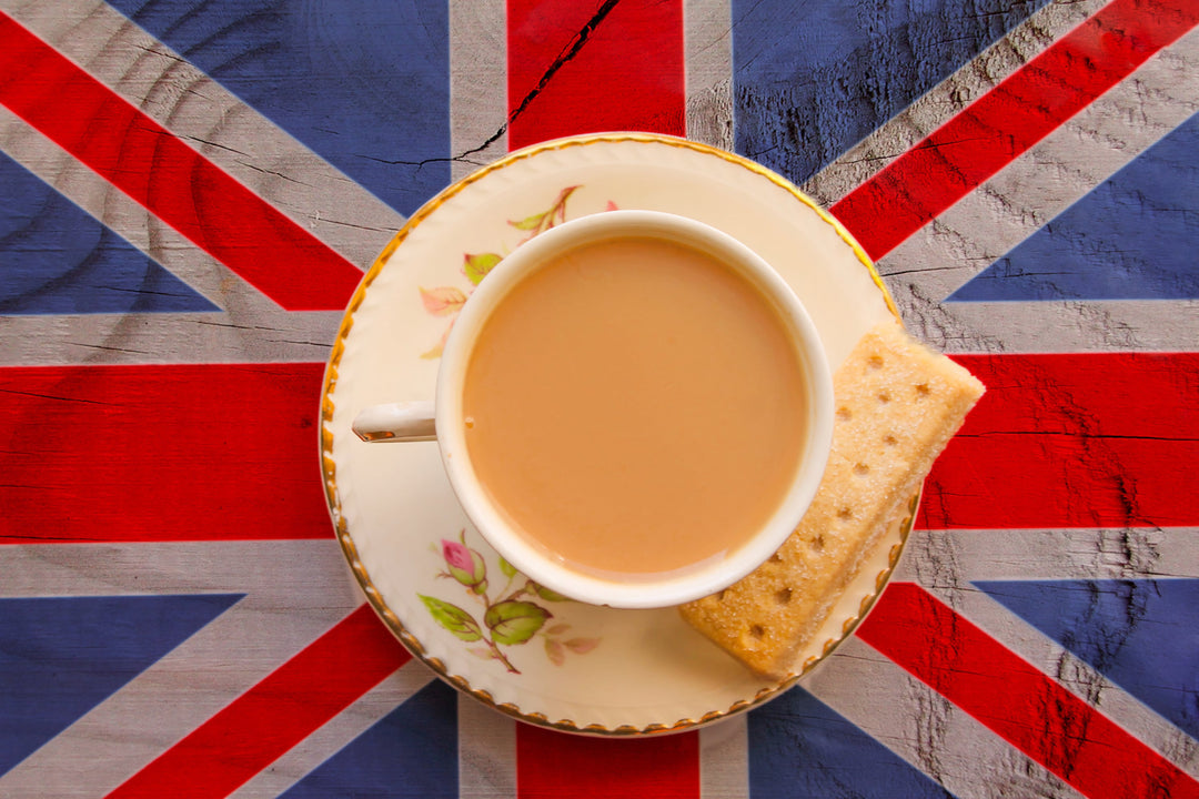 Earl-Grey Tee mit Milch und Gebäck in einer Teetasse auf einer Union Jake Flagge