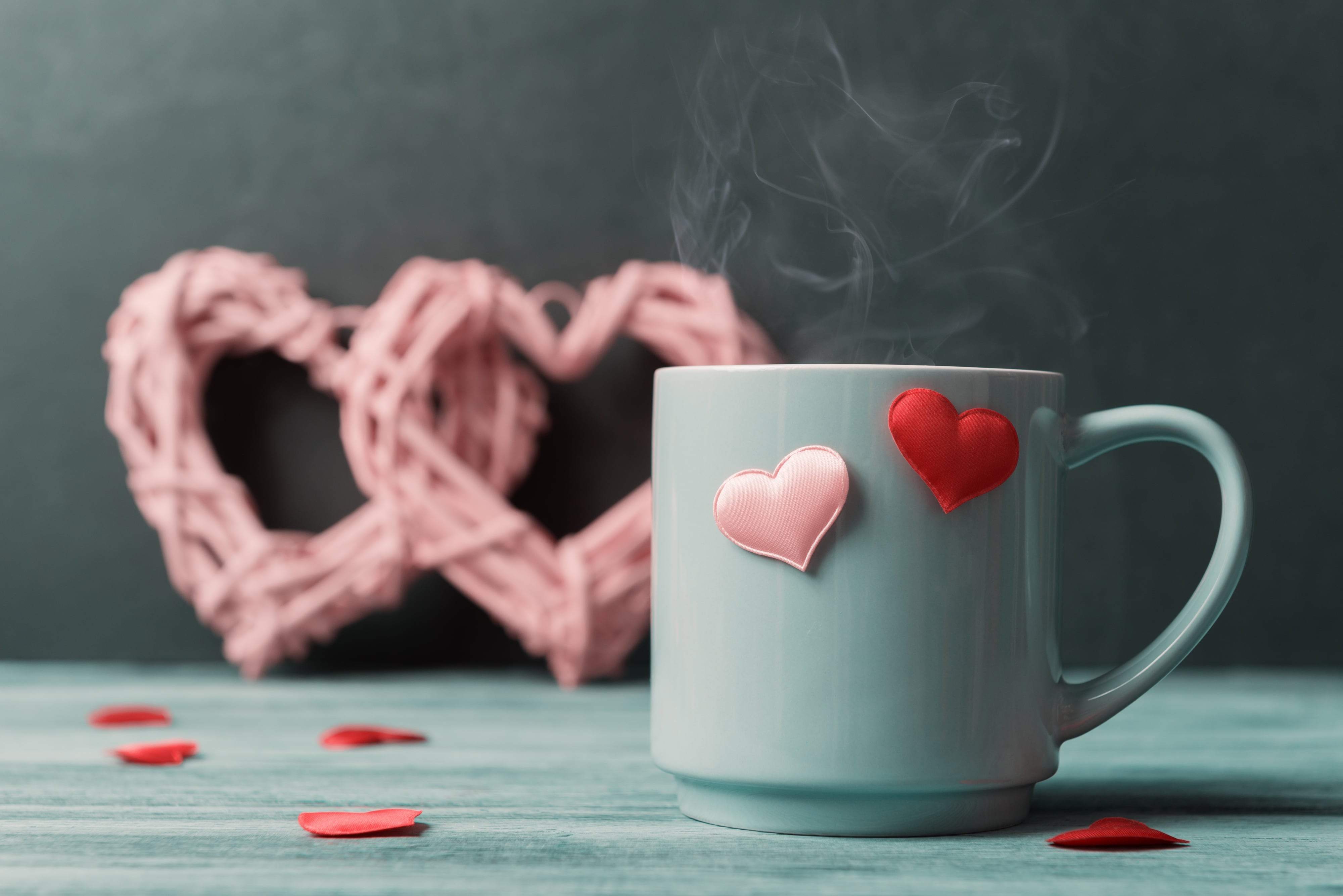 Teetasse mit Herzchen und dampfenden Tee im Hintergrund 2 rosa Deko Herzen als Bannerbild zum Thema Valentinstag